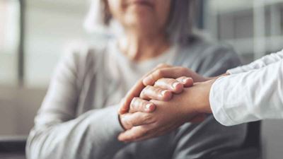 Elderly woman holds doctor's hands