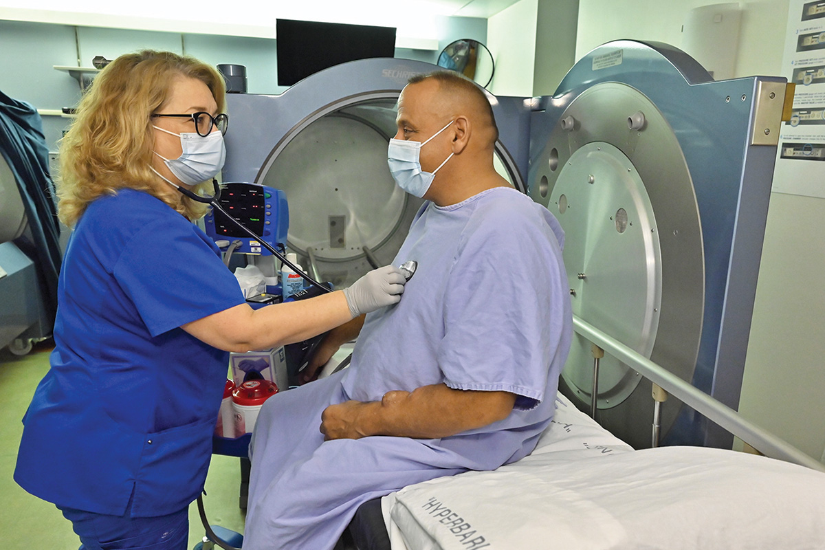 Ellen Stacom, RN, checks Patrick Bria’s heartbeat