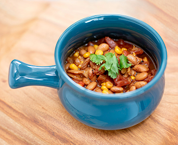 pinto bean soup with a green garnish in a blue soup bowl on a light wood surface.